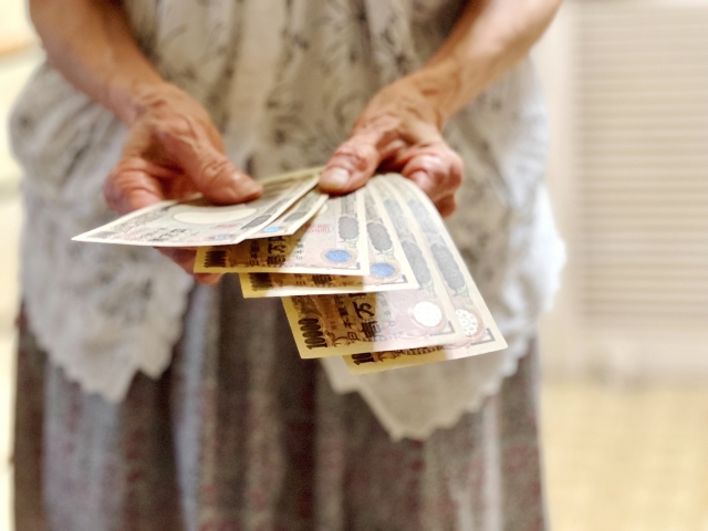 たくさんの1万円札を持つ高齢女性の手